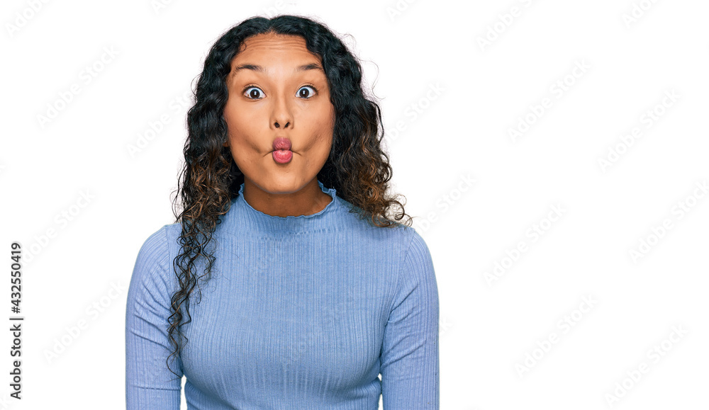Young hispanic woman with curly hair wearing casual clothes making fish face with lips, crazy and comical gesture. funny expression. Young hispanic woman with curly hair wearing casual clothes making fish face with lips, crazy and comical gesture. funny expression.