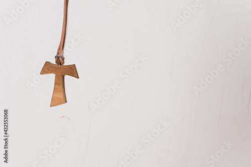 Closeup of wooden tau cross T-shaped necklace isolated on white wall background