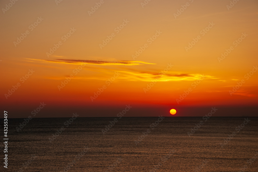 Seascape at sunset. The red disk of the sun is beyond the horizon.