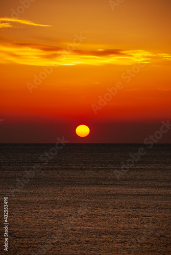 Seascape at sunset. The red disk of the sun is beyond the horizon.