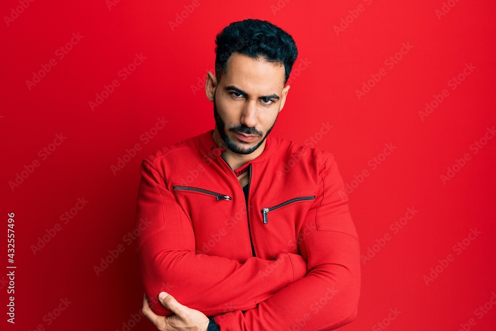 Young hispanic man wearing red leather jacket skeptic and nervous, disapproving expression on face with crossed arms. negative person.