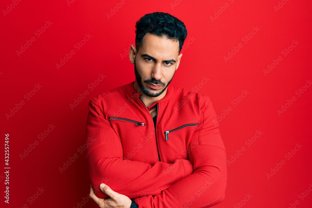 Fototapeta premium Young hispanic man wearing red leather jacket skeptic and nervous, disapproving expression on face with crossed arms. negative person.