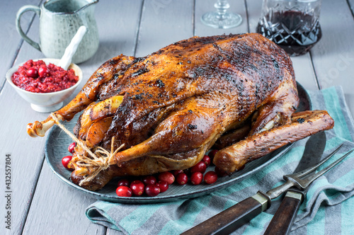 Traditional Christmas roast goose with potatoes, apple and cranberry served as close-up on a design plate photo