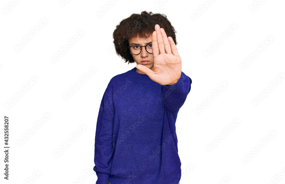 Young hispanic girl wearing casual winter sweater and glasses doing stop sing with palm of the hand. warning expression with negative and serious gesture on the face. Young hispanic girl wearing casual winter sweater and glasses doing stop sing with palm of the hand. warning expression with negative and serious gesture on the face.