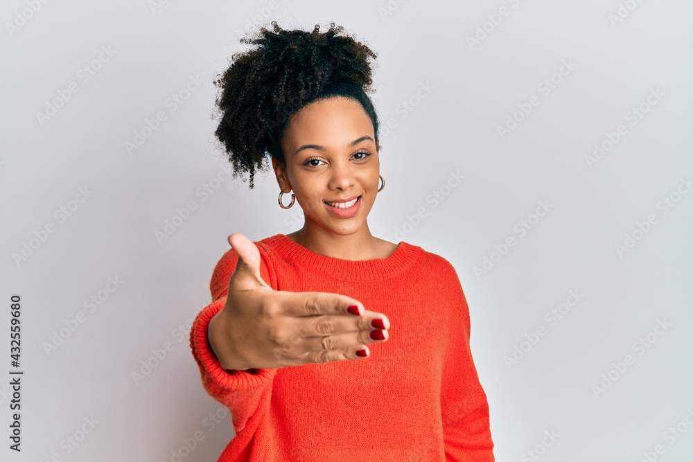 Young african american girl wearing casual clothes smiling friendly offering handshake as greeting and welcoming. successful business. Young african american girl wearing casual clothes smiling friendly offering handshake as greeting and welcoming. successful business.