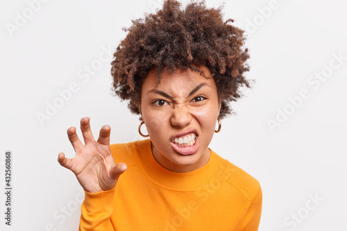 Obraz na płótnie Afro American woman makes grimace scary face holds hand as if claw clenches teet