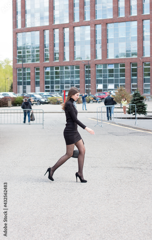 a woman runs across the road. Late for work brick business buildings a woman runs across the road. Late for work brick business buildings