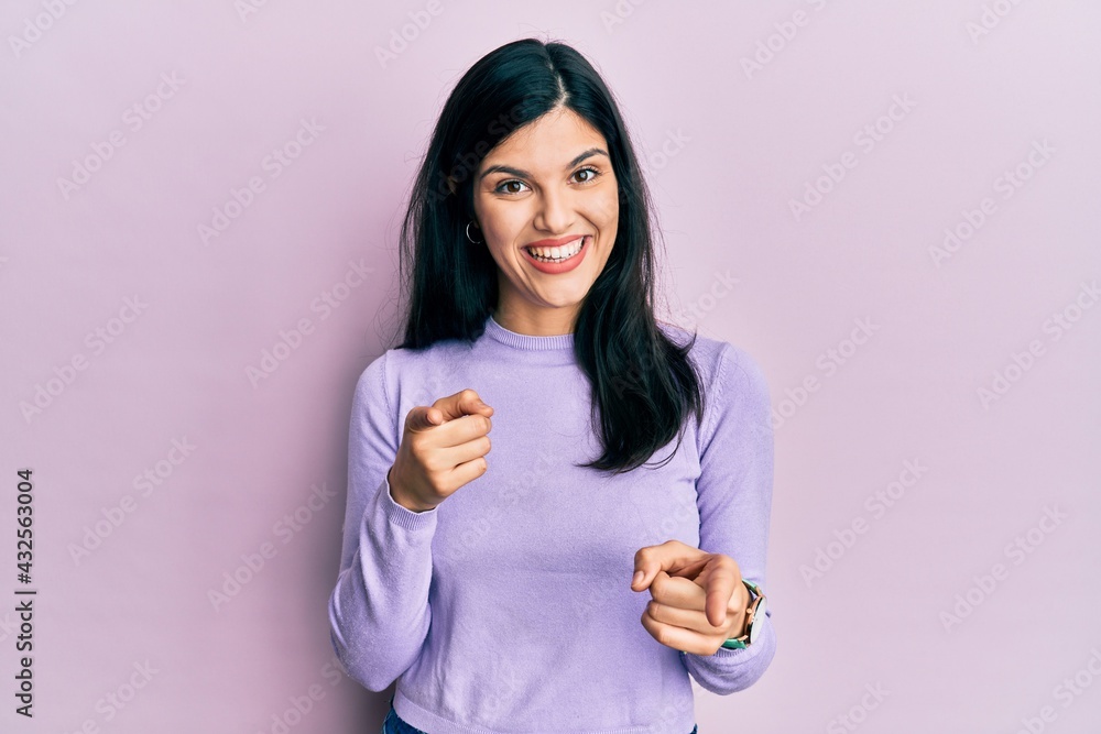 Young hispanic woman wearing casual clothes pointing fingers to camera with happy and funny face. good energy and vibes. Young hispanic woman wearing casual clothes pointing fingers to camera with happy and funny face. good energy and vibes.