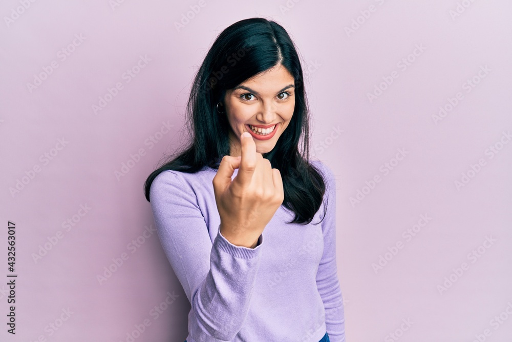 Young hispanic woman wearing casual clothes beckoning come here gesture with hand inviting welcoming happy and smiling Young hispanic woman wearing casual clothes beckoning come here gesture with hand inviting welcoming happy and smiling