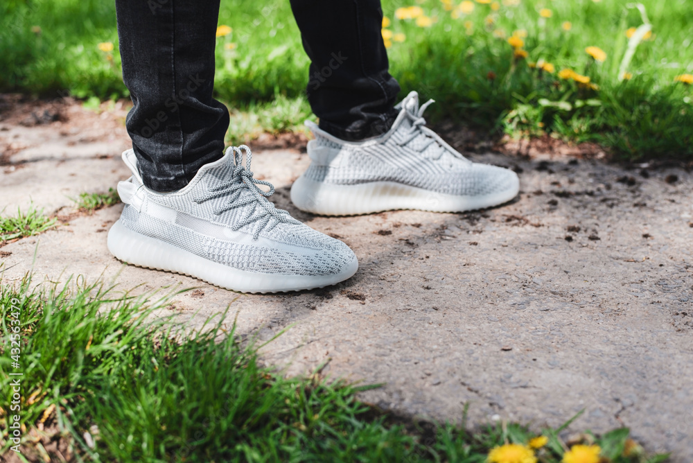 Stylish modern light sneakers made of fabric on the feet of a teenage boy walking in the park, focus on sneakers Stylish modern light sneakers made of fabric on the feet of a teenage boy walking in the park, focus on sneakers