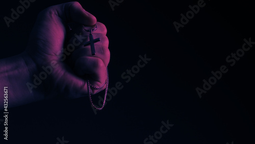 Praying with a rosary. hand of Catholic man with rosary on black background. Hands holding a silver rosary or cross pendant of Jesus Christ. Crucifix and hand on black background. Praying God concept