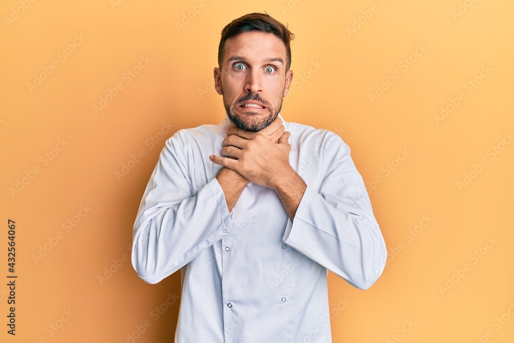 Handsome man with beard wearing professional cook uniform shouting and suffocate because painful strangle. health problem. asphyxiate and suicide concept. Handsome man with beard wearing professional cook uniform shouting and suffocate because painful strangle. health problem. asphyxiate and suicide concept.