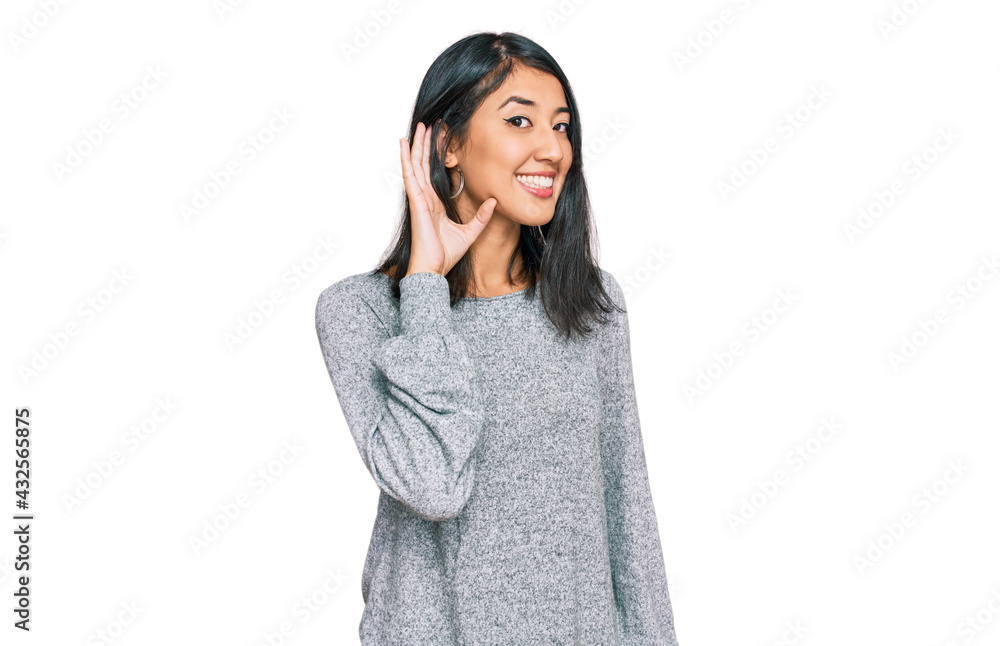 Beautiful asian young woman wearing casual clothes smiling with hand over ear listening an hearing to rumor or gossip. deafness concept. Beautiful asian young woman wearing casual clothes smiling with hand over ear listening an hearing to rumor or gossip. deafness concept.