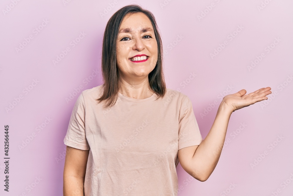 Middle age hispanic woman wearing casual clothes smiling cheerful presenting and pointing with palm of hand looking at the camera. Middle age hispanic woman wearing casual clothes smiling cheerful presenting and pointing with palm of hand looking at the camera.