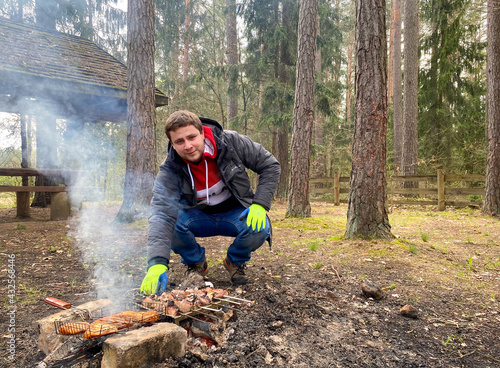 A man roasts pork and chicken shish kebab on a campfire in nature. Outdoor recreation with cooking delicious shish kebab © yarm_sasha