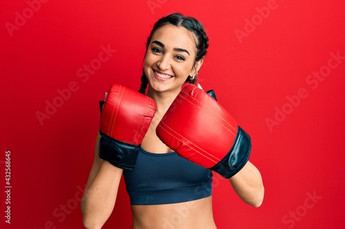 Young brunette girl using boxing gloves smiling with a happy and cool smile on face. showing teeth.