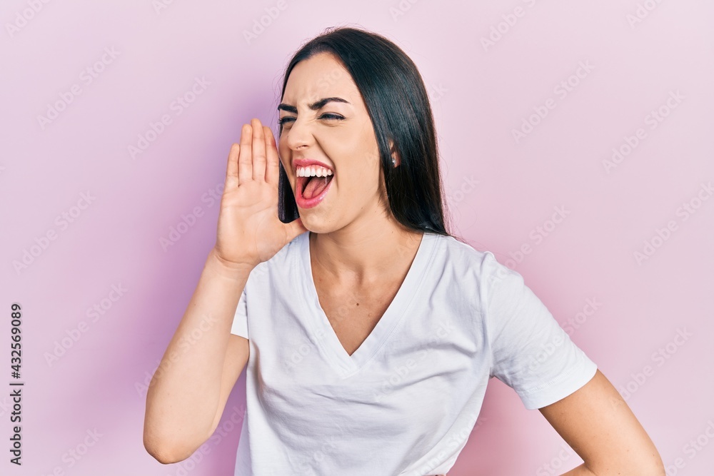 Fototapeta premium Beautiful woman with blue eyes wearing casual white t shirt shouting and screaming loud to side with hand on mouth. communication concept.