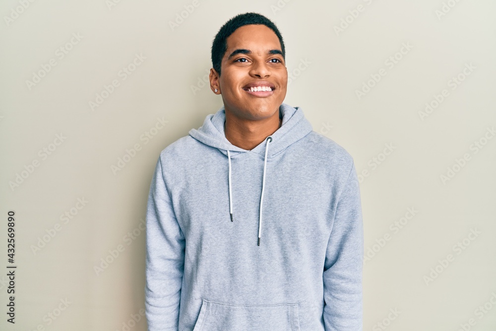Young handsome hispanic man wearing casual sweatshirt looking to side, relax profile pose with natural face and confident smile. Young handsome hispanic man wearing casual sweatshirt looking to side, relax profile pose with natural face and confident smile.