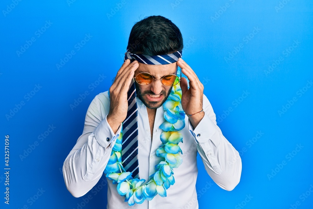 Young hispanic businessman wearing party funny style with tie on head with hand on head for pain in head because stress. suffering migraine. Young hispanic businessman wearing party funny style with tie on head with hand on head for pain in head because stress. suffering migraine.