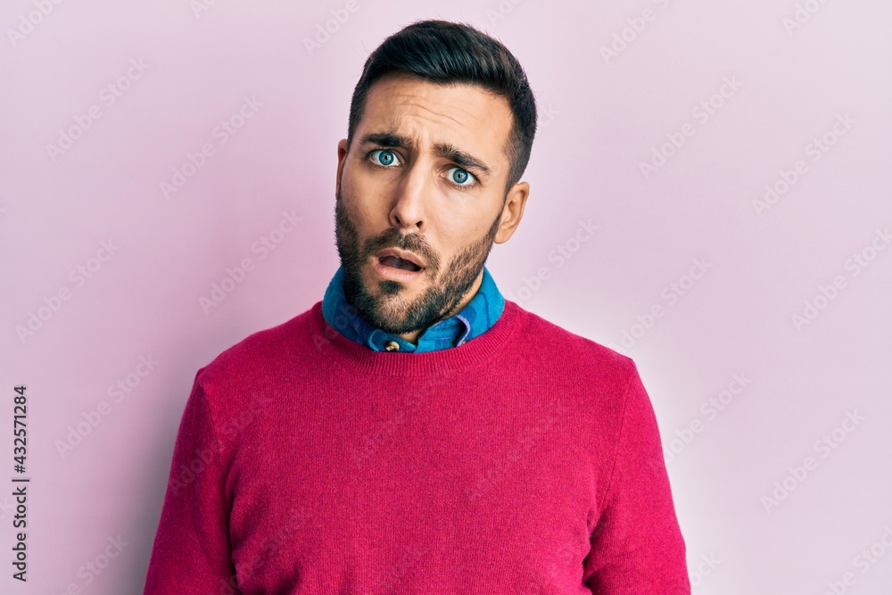 Fototapeta premium Young hispanic man wearing casual clothes in shock face, looking skeptical and sarcastic, surprised with open mouth