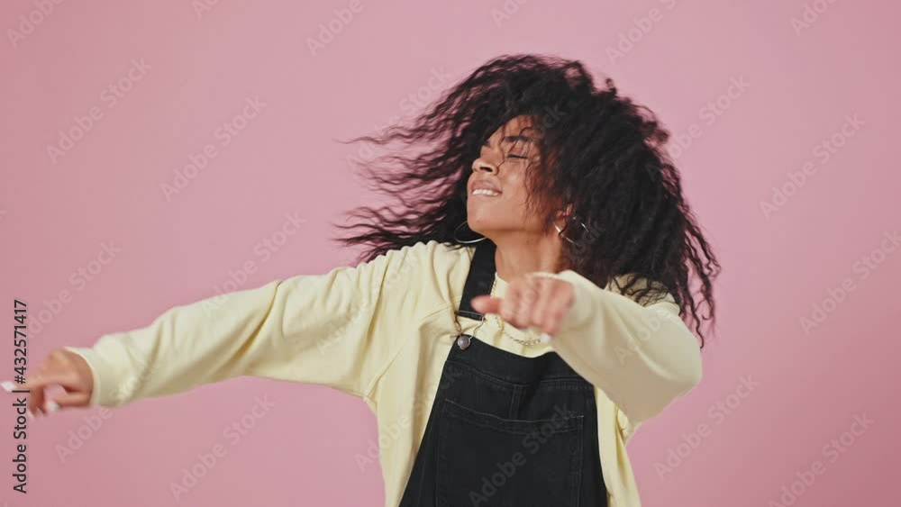 Disco fun. Studio portrait of happy carefree african american lady with curly hair dancing over violet background