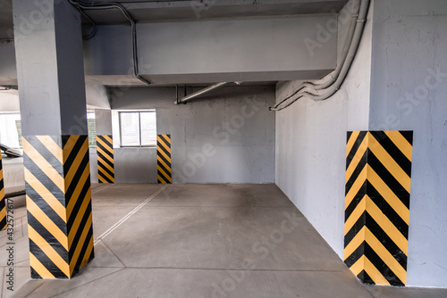 An empty underground garage, yellow-black striped posts, gray walls.