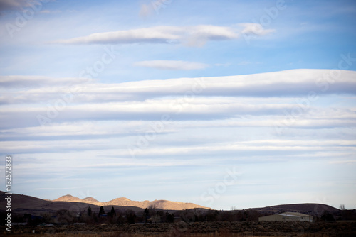 Landscape orientation three quarters of a sky filled with lenticular clouds over desert town carson city