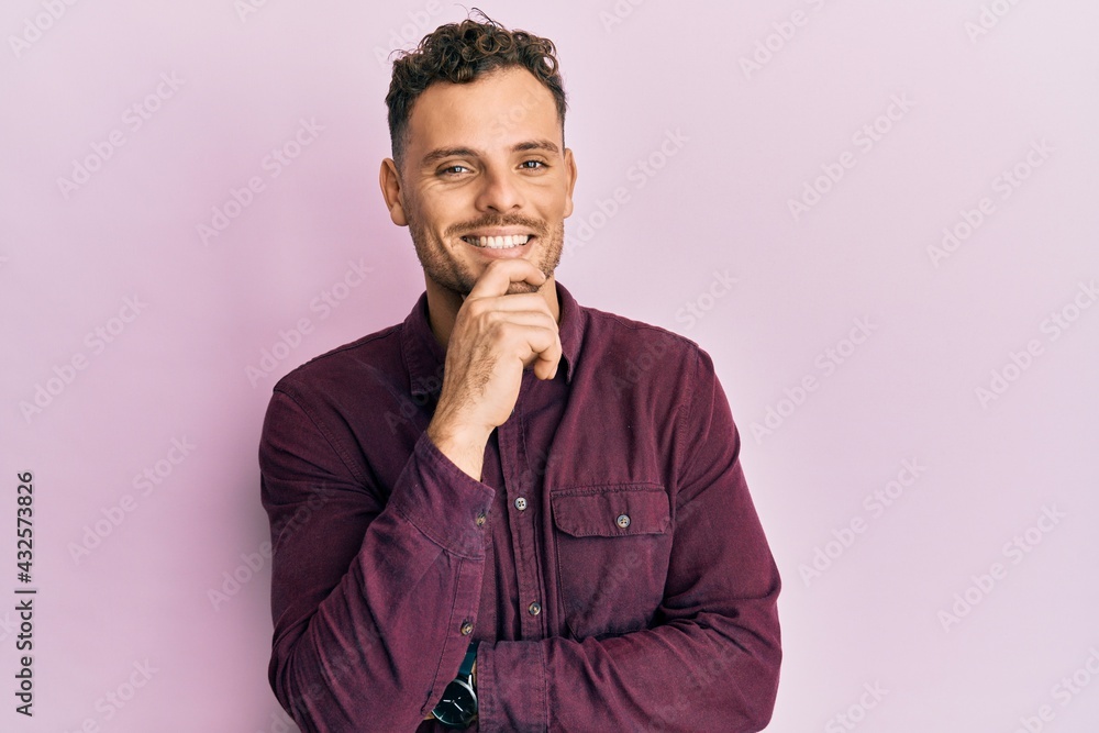 Young hispanic man wearing casual clothes smiling looking confident at the camera with crossed arms and hand on chin. thinking positive. Young hispanic man wearing casual clothes smiling looking confident at the camera with crossed arms and hand on chin. thinking positive.