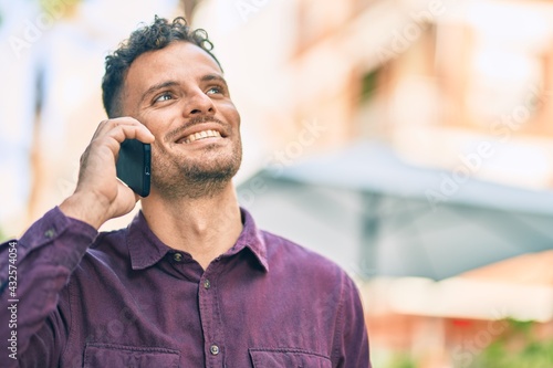 Young hispanic man smiling happy talking on the smartphone at the city.