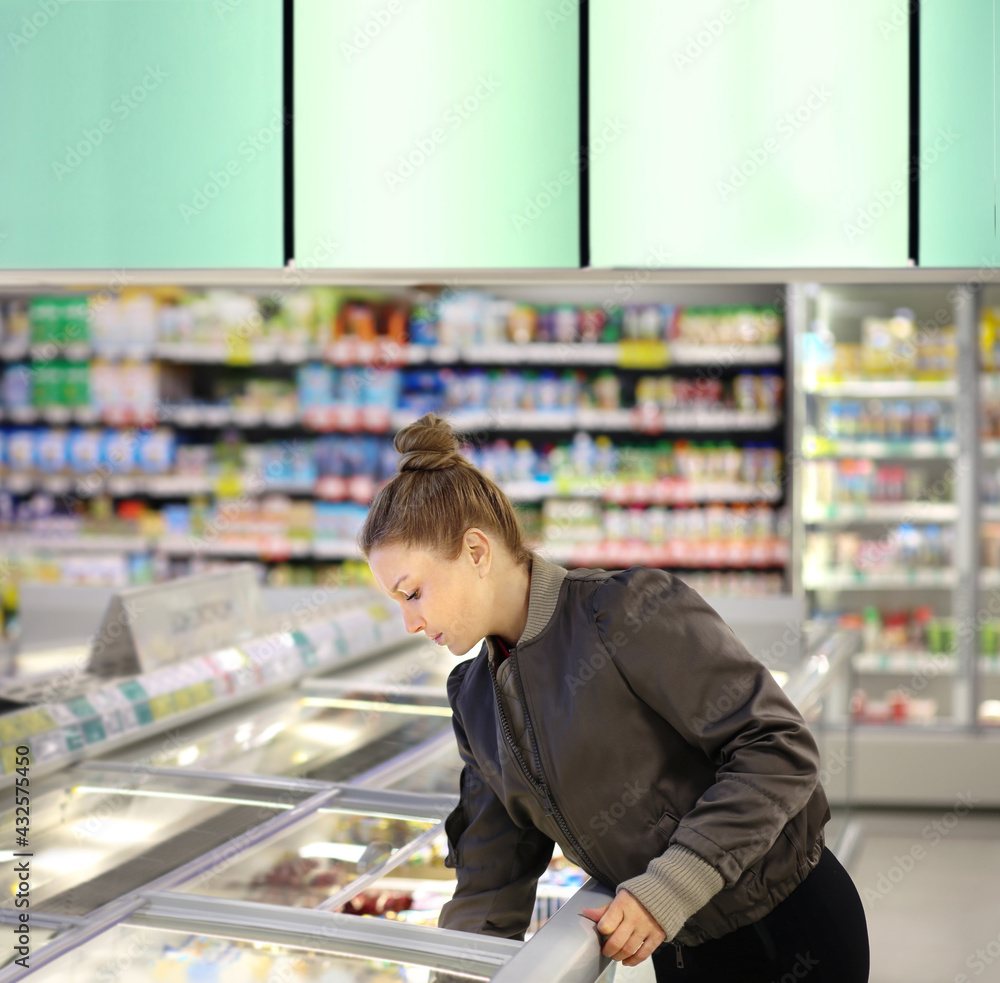 Woman choosing frozen food from a supermarket freezer