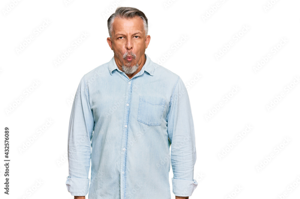Middle age grey-haired man wearing casual clothes making fish face with lips, crazy and comical gesture. funny expression. Middle age grey-haired man wearing casual clothes making fish face with lips, crazy and comical gesture. funny expression.