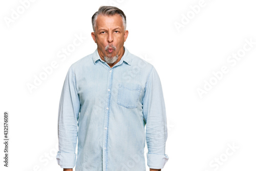Middle age grey-haired man wearing casual clothes making fish face with lips, crazy and comical gesture. funny expression.