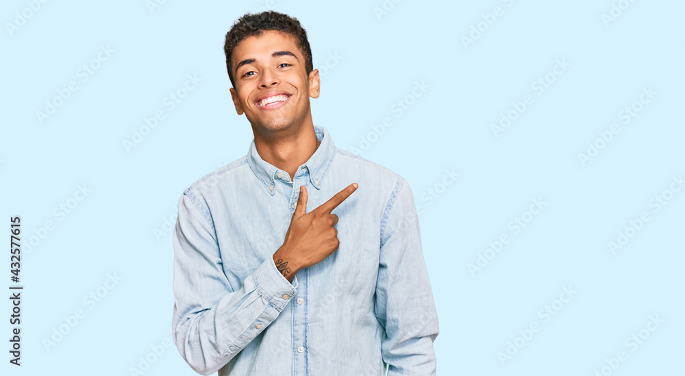 Young handsome african american man wearing casual clothes cheerful with a smile of face pointing with hand and finger up to the side with happy and natural expression on face Young handsome african american man wearing casual clothes cheerful with a smile of face pointing with hand and finger up to the side with happy and natural expression on face