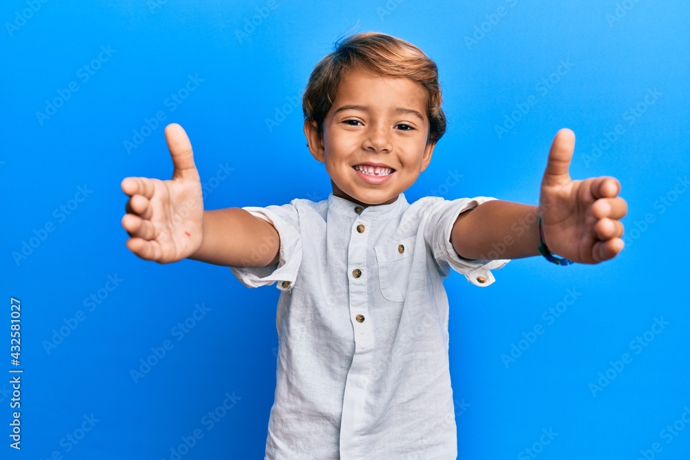 Adorable latin kid wearing casual clothes looking at the camera smiling with open arms for hug. cheerful expression embracing happiness. Adorable latin kid wearing casual clothes looking at the camera smiling with open arms for hug. cheerful expression embracing happiness.