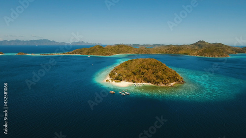 Aerial view of tropical beach on the island Banana, Philippines. Beautiful tropical island with sand beach, palm trees. Tropical landscape: beach with palm trees. Seascape: Ocean, sky, sea. Travel