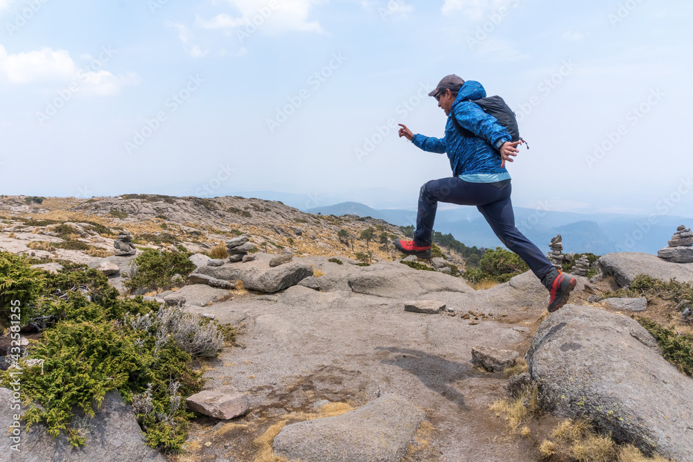 A Hispanic hiker jumping up on mount Tlaloc under a cloudy sky in Mexico