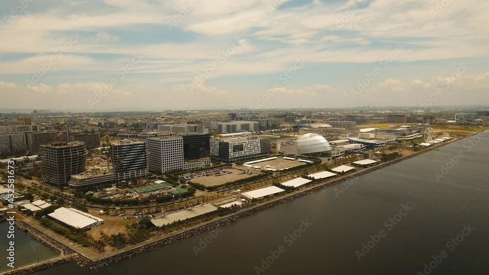 Fototapeta premium Aerial view of Manila city. Fly over city with skyscrapers and buildings n Mall of Asia. Aerial skyline of Manila. Modern city by sea, highway, cars, skyscrapers, shopping malls. Makati district