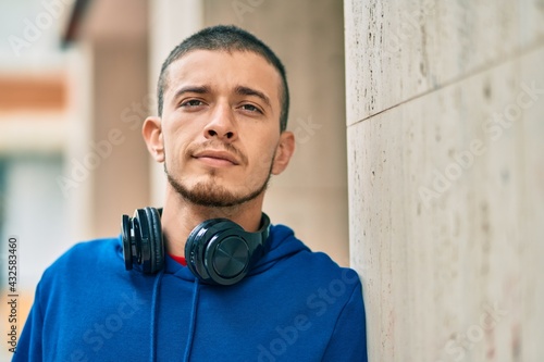 Young hispanic man smiling happy using headphones at the city