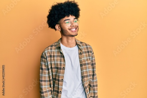 Young african american man with afro hair wearing casual clothes looking to side, relax profile pose with natural face and confident smile.