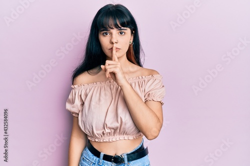 Young hispanic girl wearing casual clothes asking to be quiet with finger on lips. silence and secret concept.