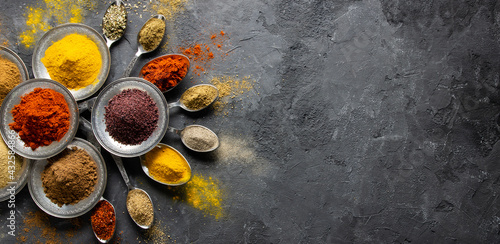 Assortment of natural spices on a vintage silver spoons or dishes on dark rustic stone background, Healthy spice concept