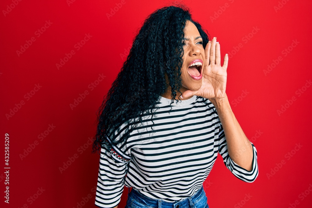 Middle age african american woman wearing casual clothes shouting and screaming loud to side with hand on mouth. communication concept. Middle age african american woman wearing casual clothes shouting and screaming loud to side with hand on mouth. communication concept.