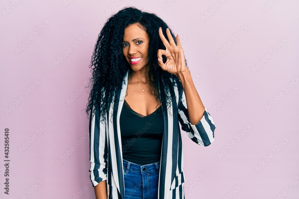 Middle age african american woman wearing casual clothes smiling positive doing ok sign with hand and fingers. successful expression.