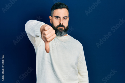Young hispanic man wearing casual clothes looking unhappy and angry showing rejection and negative with thumbs down gesture. bad expression.