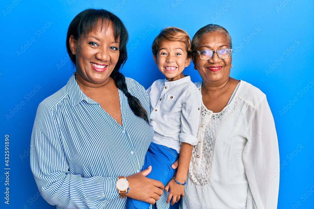 Hispanic family of grandmother, mother and son hugging together looking positive and happy standing and smiling with a confident smile showing teeth Hispanic family of grandmother, mother and son hugging together looking positive and happy standing and smiling with a confident smile showing teeth
