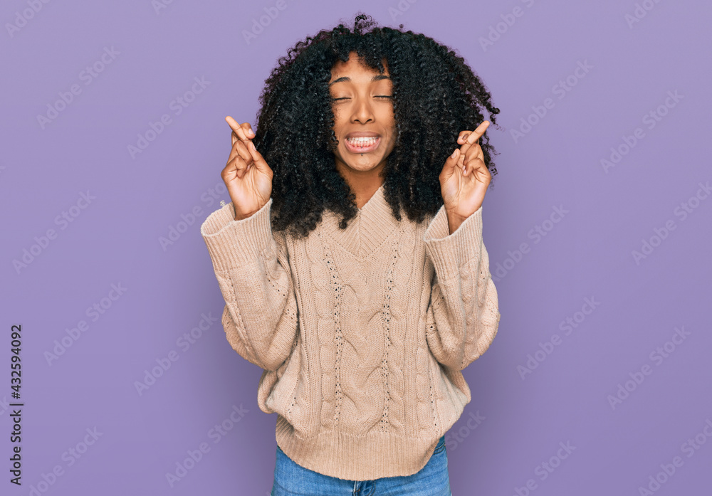 Young african american girl wearing casual clothes gesturing finger crossed smiling with hope and eyes closed. luck and superstitious concept. Young african american girl wearing casual clothes gesturing finger crossed smiling with hope and eyes closed. luck and superstitious concept.