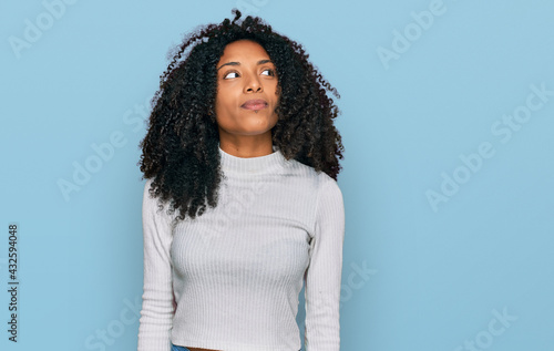 Young african american girl wearing casual clothes smiling looking to the side and staring away thinking.