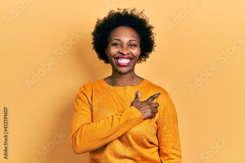 Young african american woman wearing casual clothes cheerful with a smile on face pointing with hand and finger up to the side with happy and natural expression