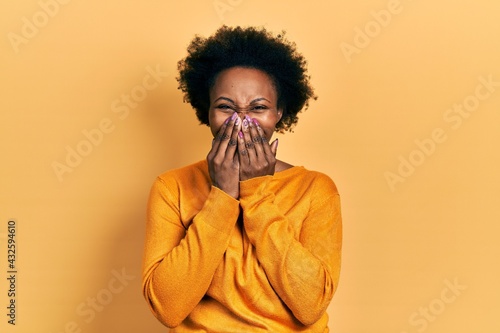 Young african american woman wearing casual clothes laughing and embarrassed giggle covering mouth with hands, gossip and scandal concept © Krakenimages.com