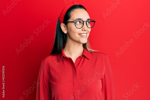 Young hispanic woman wearing casual clothes and glasses looking to side, relax profile pose with natural face and confident smile.